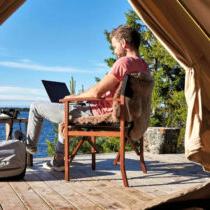 Photo of a man in a glam tent working on a lap top